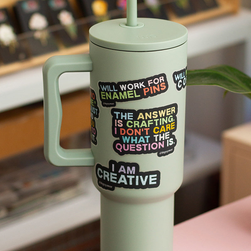 Mint green insulated tumbler adorned with bold colorful quote stickers about creativity.