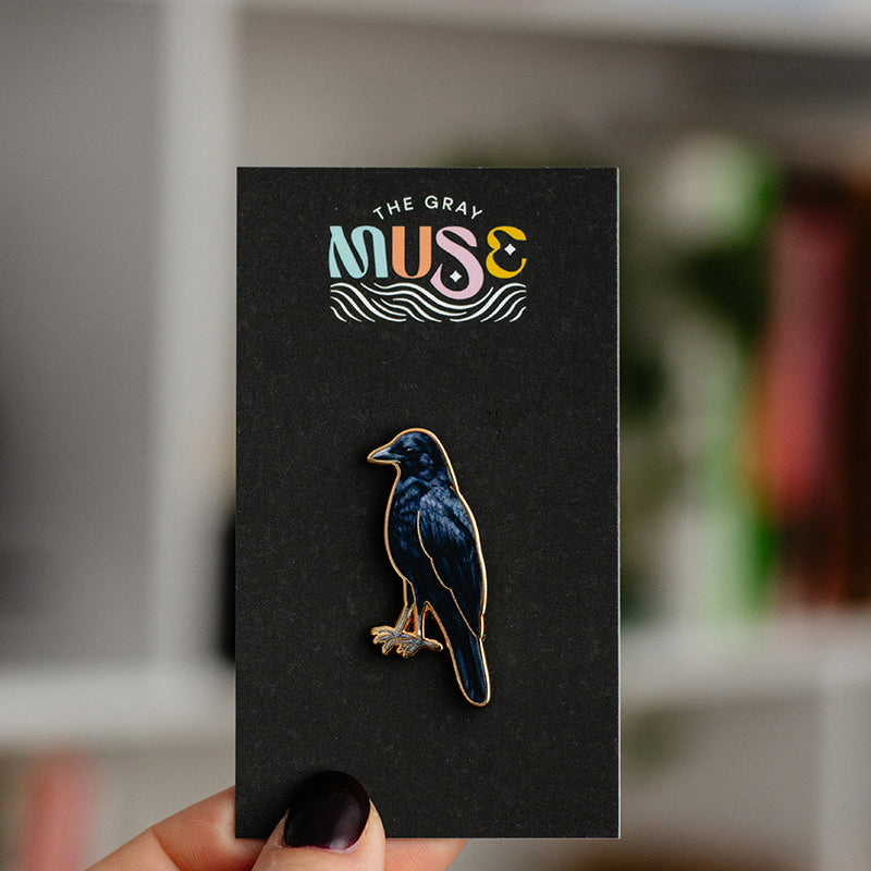 American crow enamel pin with a dark blue body on a black display card