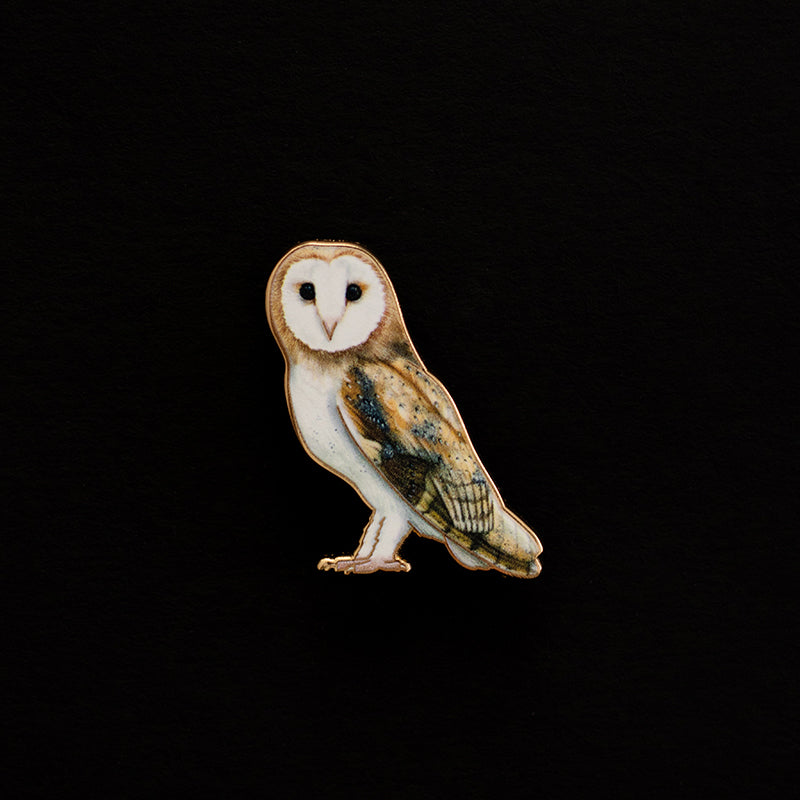 Barn Owl enamel pin centered on a black background with a white face and brown tan body.