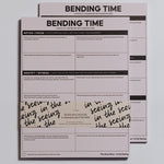 Bending Time Notepad in soft pink with bold header and grid prompts, two sheets overlapped with a handwritten wrap.