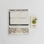 Energetic Capacity Bundle on a clean desk featuring Energy Leaks Tracker notepad and a small energy keychain in packaging.