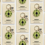 Several Energy interactive enamel keychains displayed on individual beige cards in a neat grid