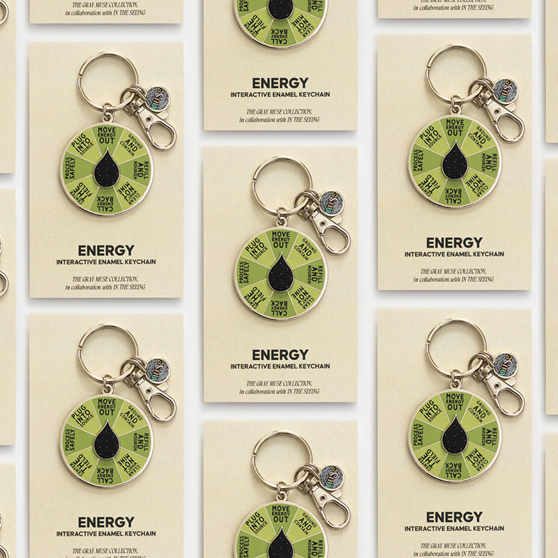 Several Energy interactive enamel keychains displayed on individual beige cards in a neat grid