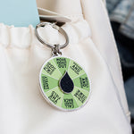 Energy spinner enamel keychain featuring a green segmented wheel with a black teardrop center on a silver ring.