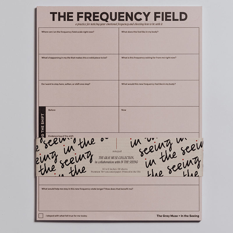The Frequency Field Notepad pink page with a grid of prompts for emotional awareness and a wraparound band