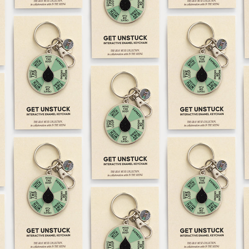 Grid of Get Unstuck enamel keychains on beige cards displayed as product collection