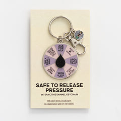 It's Safe to Release Pressure spinner enamel keychain displayed on a beige display card