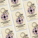 Promotional card displays Safe to Release Pressure enamel keychain with a purple segmented spinner and silver ring