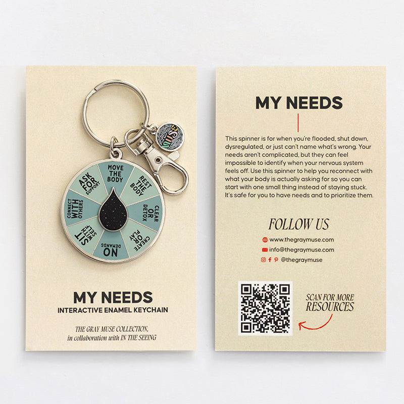 My Needs interactive enamel keychain with teal segmented spinner and black center on beige packaging front and back card visible.