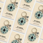 Collage of multiple My Needs spinner keychain cards arranged in a grid with teal spinners visible.