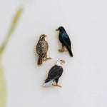 Three enamel bird pins Red-Tailed Hawk American Crow and Bald Eagle on a white backing card