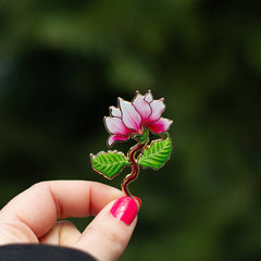 Pink Magnolia enamel pin with gold trim and green leaves, 1.75 inches tall.