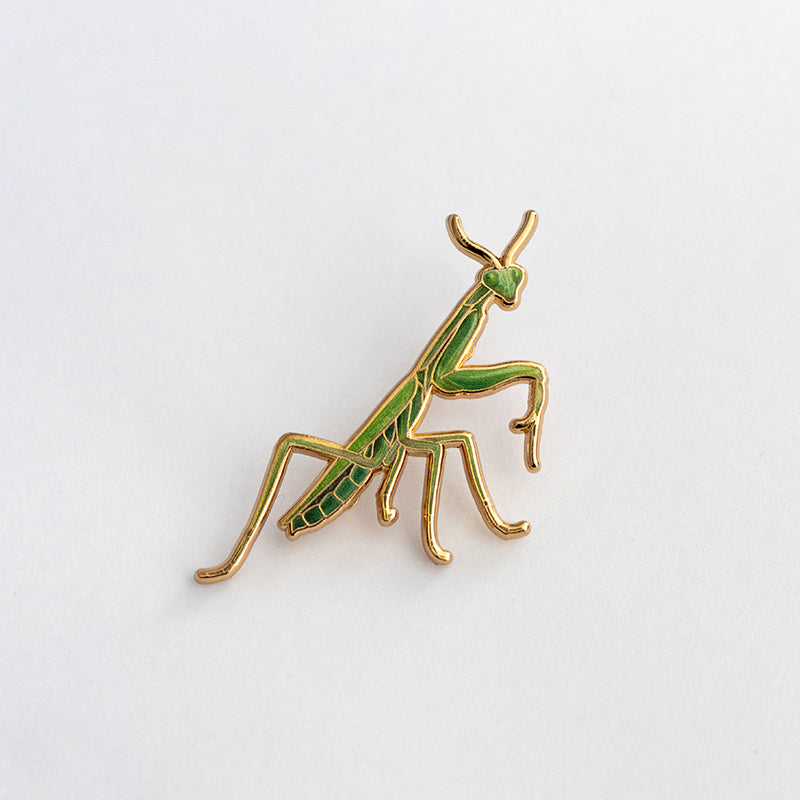 Praying Mantis enamel pin on white background with green and gold detailing; state insect of CT and SC.