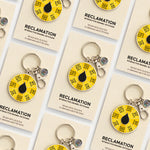 Multiple Reclamation interactive enamel keychains arranged on beige display cards featuring yellow spinner dials.