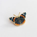 Close-up of a Red Admiral butterfly enamel pin on a plain white background