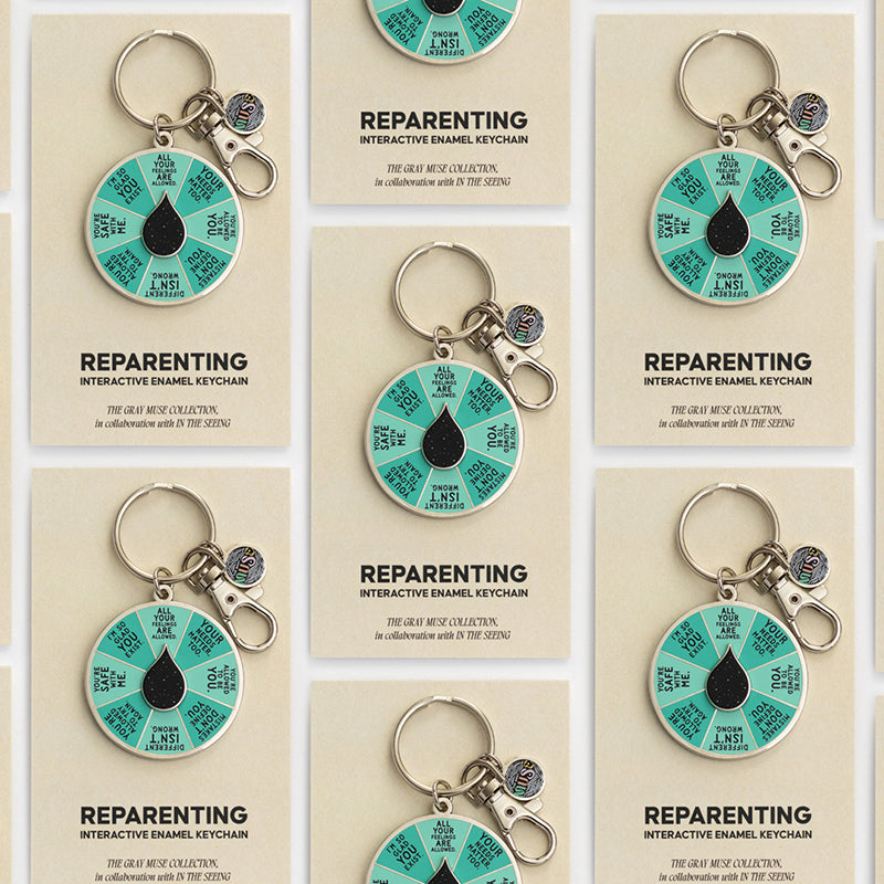 Reparenting interactive enamel keychain with teal segmented spinner and metal ring on a beige card.