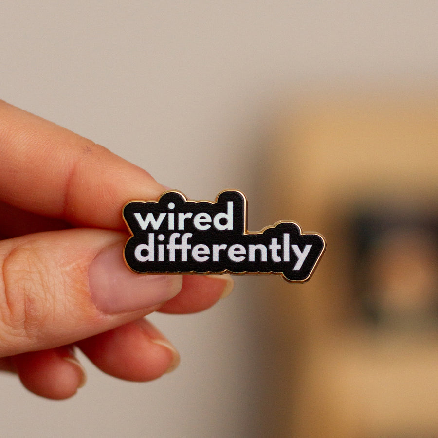 Wired differently enamel pin being held
