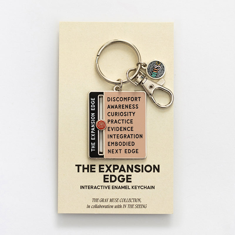 Expansion Edge enamel keychain with pink panel and black edge label on beige display card with keys and a round charm.