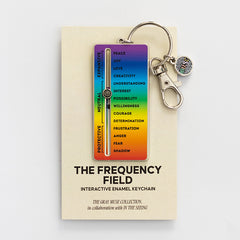 The Frequency Field interactive enamel keychain with a rainbow slider mounted on a display card.