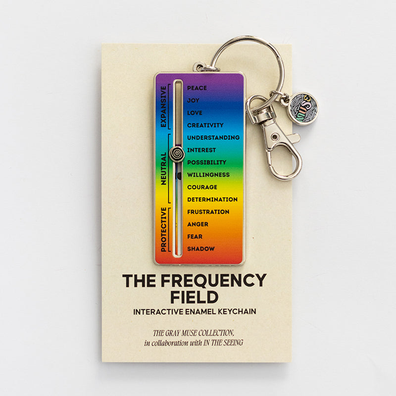 The Frequency Field interactive enamel keychain with a rainbow slider mounted on a display card.