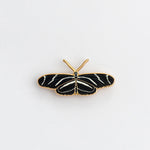 Zebra Longwing butterfly enamel pin with black and white striped wings and gold edge on a white background